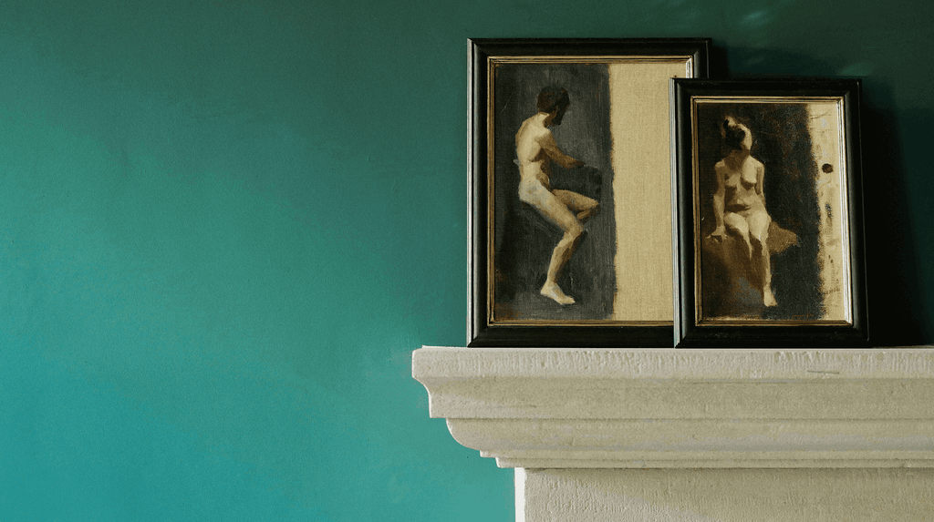 framed oil paintings on mantlepiece against rich green painted wall