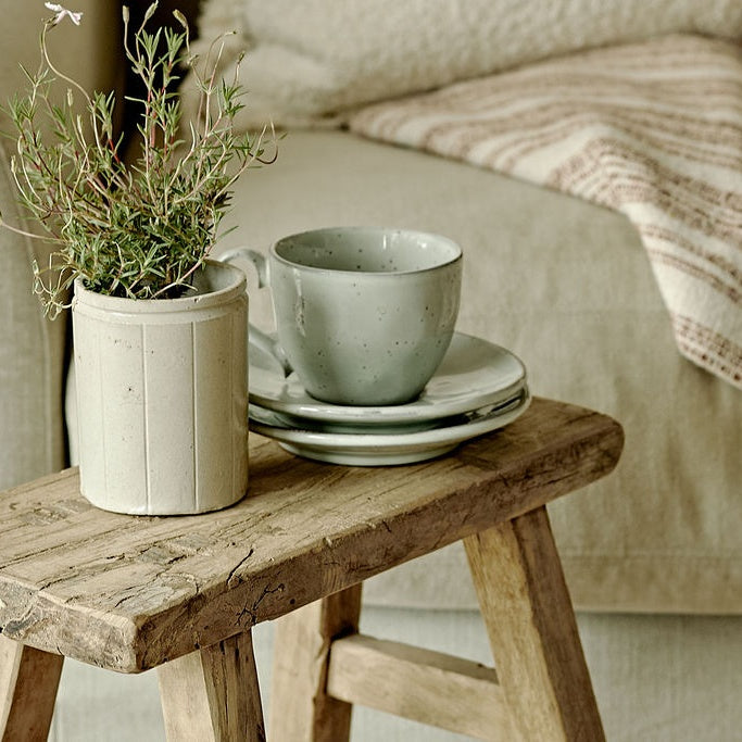 vintage wooden stool with plant pot and ceramic cup on top