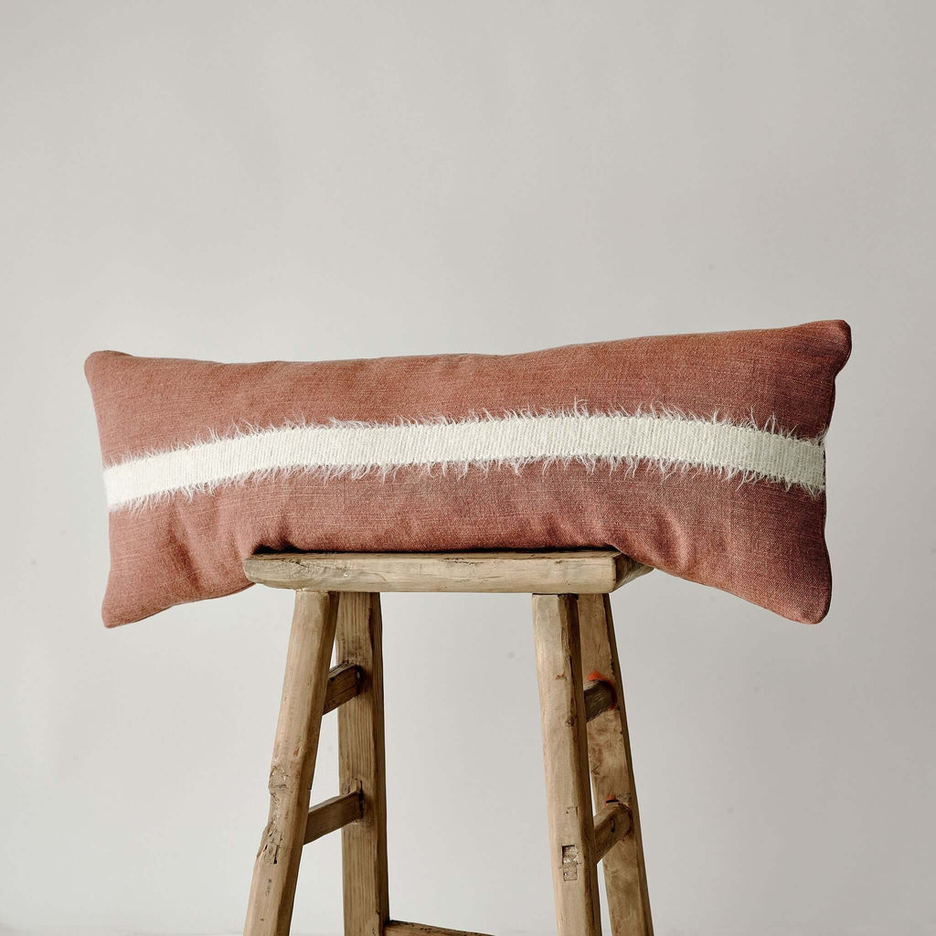 bourton bolster cushion in red with cream strip on vintage bench